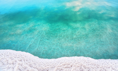 Shore of Dead sea in Ein Bokek, Israel, white salt crystals outside and at the bottom, turquoise...
