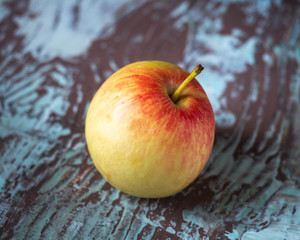 Single yellow-red apple on motley wooden background
