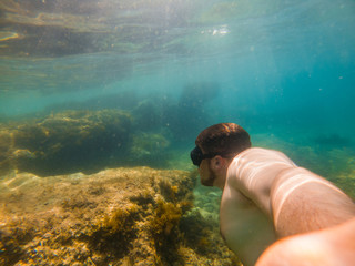 man swimming underwater with snorkeling musk