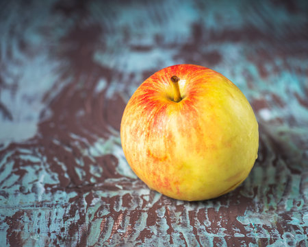 Ripe apple on a variegated wooden background, blurred focus
