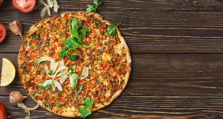 Turkish pizza lahmajun with minced lamb and beef on a thin crust with vegetables and herbs,...