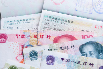 Close up of approved China travel Visa and Chinese currency (Yuan) banknotes money.