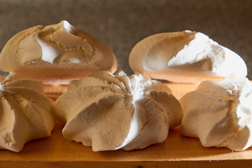 Off white marshmallow roses on wooden surface. Delicious homemade meringue cakes. The concept of home cooking of food.