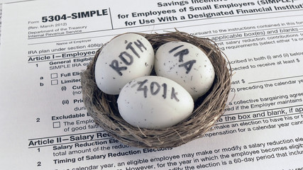 Fototapeta na wymiar Conceptual composition. Pension savings. Individual retirement account. Three eggs with the inscriptions IRA, 401k, Roth lie in the nest against the background of the 5304-SIMPLE form. Close-up
