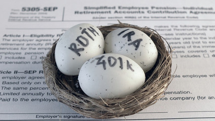 Fototapeta na wymiar Conceptual composition. Pension savings. Individual retirement account. Three eggs with the inscriptions IRA, 401k, Roth lie in the nest against the background of the 5305-SEP form. Close-up