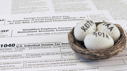 Conceptual composition. Pension savings. Individual retirement account. Three eggs with the inscriptions IRA, 401k, Roth lie in the nest against the background of the 1040 form. Close-up