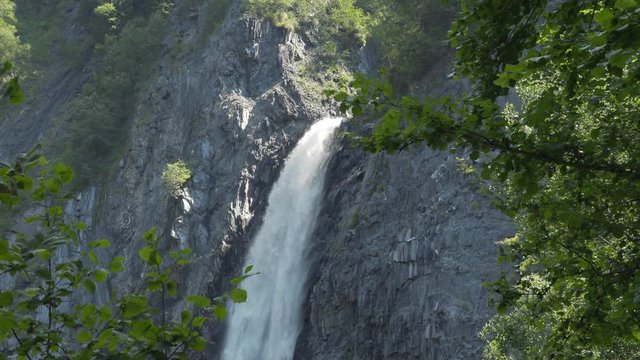 Static shot of one of Venosc's hidden waterfalls among trees, in the French Alps. 4K