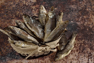 stewed river fish lying in a basket on a dark background. Traditional beer snack.