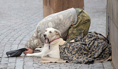 Beggar with dog begging for alms on the street in Prague