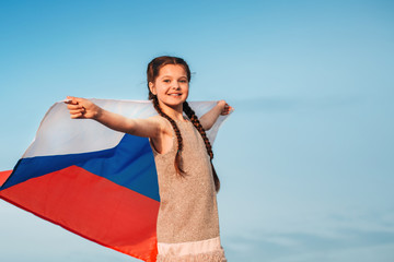 A Russian flag flies in the hands of a teenage girl against a purple sky at sunset on a summer evening . Russian flag day August 22