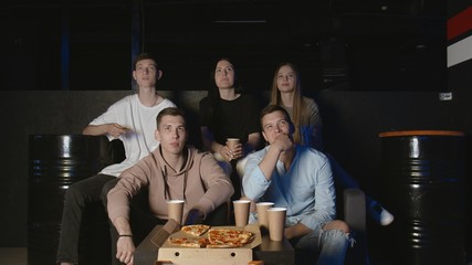 Young friends eats pizza and watchs funny entertainment TV show