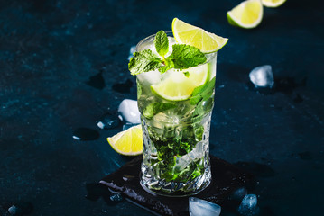 Mojito cocktail or mocktail with lime, mint, and ice in glass on blue background. Summer cold alcoholic non-alcoholic drink,  beverage and cocktail. Copy space