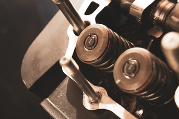 Car engine cylinder head repair. Close-up of the engine valve and camshaft. Industrial background.