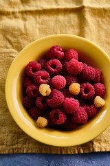 Raspberries in a yellow plate. Copy space.