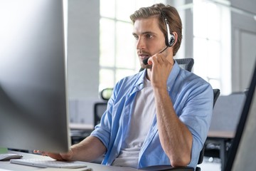 Young handsome male customer support phone operator with headset working in call center.