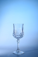 Wineglass on the light background. Fine cristal glassware concept. Vertical, toned in blue