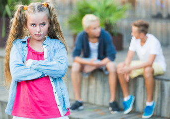 Portrait of offended girl not talking with friends after quarrel outdoors