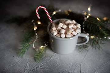 Christmas Setting with Hot Chocolate in a Fancy Sweater Mug with Marshmallows, Candy Canes, Wooden Deer and Xmas Lights on the Background