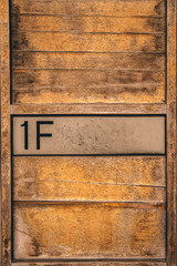 Wooden mailbox with "1F" sign on it. Toned image.