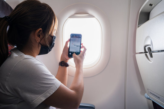 Young Woman Wearing Face Mask On An Airplane Travel Concept New Normal Background.during Coronavirus Or Covid-19 Virus Outbreak A New Normal Concept.