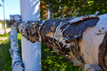 wooden fence near the house made of wooden beams and boards in a field in summer in a Russian village
