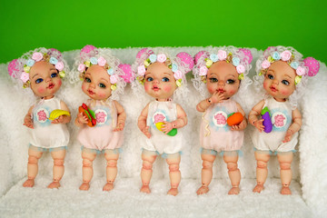 Collection of adorable handcrafted ball-jointed dolls that stand in a row on shaggy white surface...