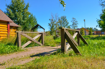 wooden bridge near the house made of wooden beams and boards in a field in summer in a Russian village