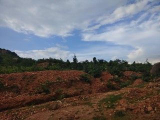 Red soil and forest with blue cloud