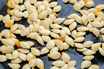 Fresh wet raw pumpkin seeds on black. Top view.