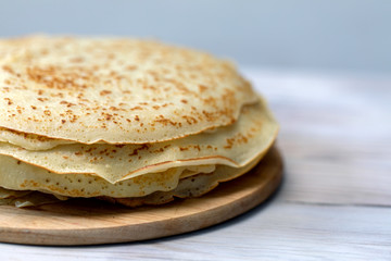 fried pancakes are stacked on wooden plate with copy space, close up