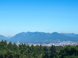 Fototapeta na wymiar Vancouver skyline and mountains seen from Queen Elizabeth Park on a sunny summer day.