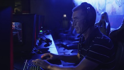Old man playing on computer late at night in Modern computer club. © stanis88