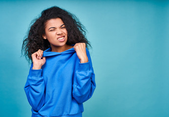 A funny teenage girl in a casual blue sweatshirt making grimaces.