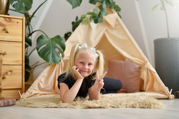 Little girl in her room on the floor next to the wigwam tent © pridannikov