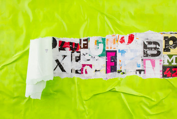 Torn and peeling green paper poster on colorful collage from clippings with letters and numbers...
