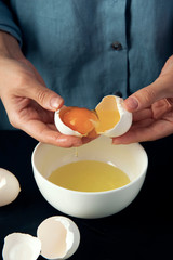 Woman breaks egg into bowl. Cooking process. Bakery making. Cottage cheese casserole making.