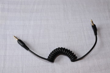 Wires and cables of some electronic devices. Headphone jack and connectors lying on the bed.