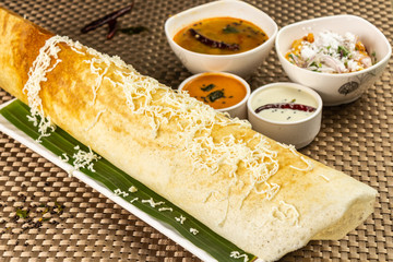 Cheese Masala dosa with different types of chutney and sambar. This is a closeup shot of one of the most famous Indian snack.