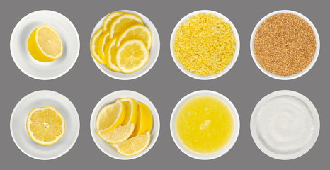 Fresh and processed lemons in white glass bowls, isolated over gray. Lemon halves, wedges and slices, freshly grated and dried lemon zest, juice and crystalline citric acid. Close up from above. Photo