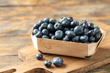 Blueberries in a wooden box on a brown wooden table. Fresh blueberries in a box. Space for text	