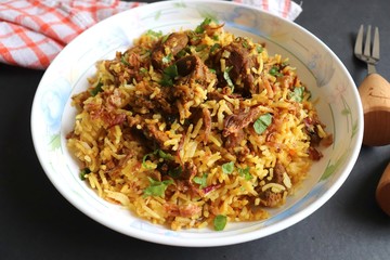 Mutton Biryani or Lamb Pulao. Garnished with fried onion & chopped coriander. Biryani is a famous Spicy non vegetarian dish of India. Goat meat cooked along with Basmati rice & spices.