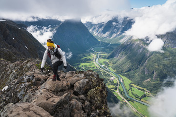 Asian woman hiker and traveller walking on narrow ridge of Romsdalseggen hiking trail in summer season, Norway, Scandinavia