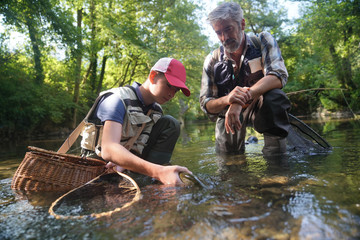 a father and his son fly fishing and catch a beautiful rainbow trout