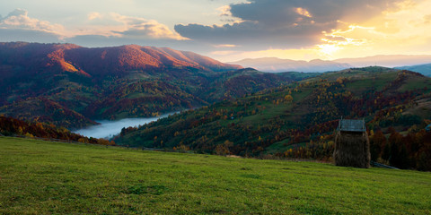 foggy morning in autumn mountains. countryside scenery in fall colors. colorful trees on the hillside. landscape beneath a sky with clouds at sunrise