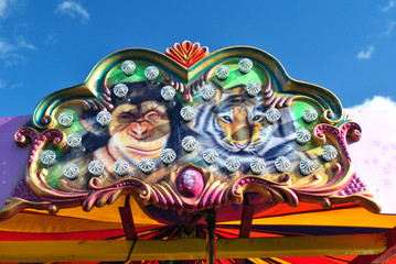 Colourful Fairground Sign with Chimpanzee & Tiger against Blue Sky 