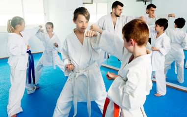 Fototapeta na wymiar Happy children training in pairs to practice new technique at karate classes