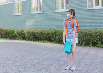 Trauriges Schulmädchen zurück zur Schule. Porträt eines müden Kindes mit Rucksack und Notizbuch