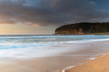 Sunrise at the beach with waves and clouds