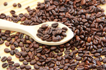natural black coffee beans in a wooden spoon