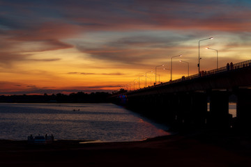Fototapeta na wymiar Silhouette of a bridge stretching across a twilight river at Lam Pao Dam, Kalasin Province, Thailand